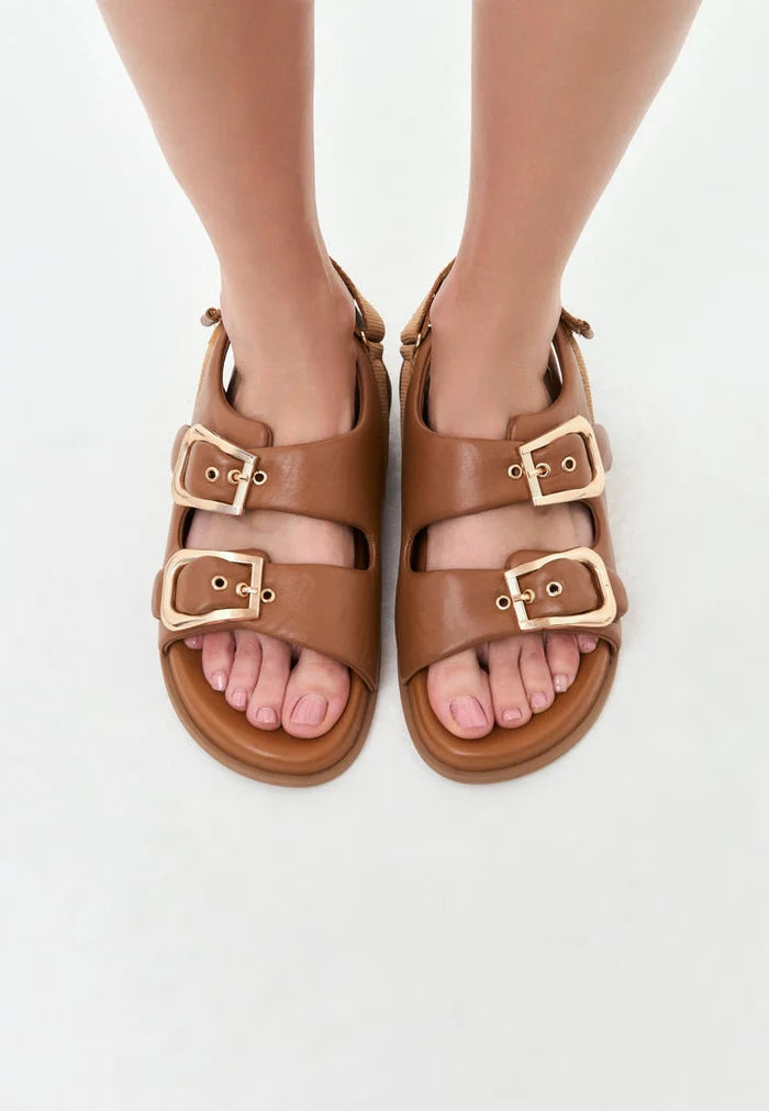 A pair of stylish beige women's wedge sandals with bold buckle detailing, perfect for summer footwear.