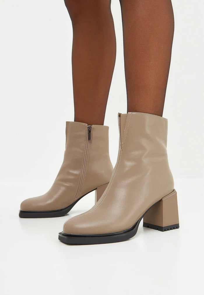 A stylish pair of women's casual high heeled beige ankle boots, perfect for adding a fashionable touch to any outfit.