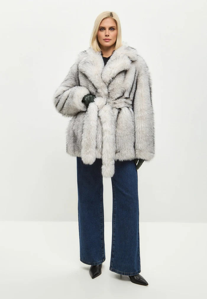 A stylish woman wearing a trendy white faux fur coat, showcasing chic outerwear fashion for the winter season.