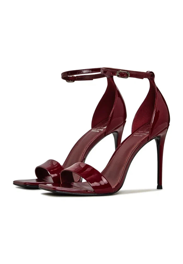 A pair of elegant patent leather ankle-strap heels in classic red, the perfect women's high heels for a timeless fashion footwear look.