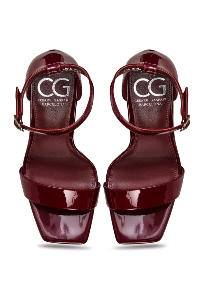 A pair of elegant patent leather ankle-strap heels in classic red, essential women's high heels for a timeless fashion footwear look.