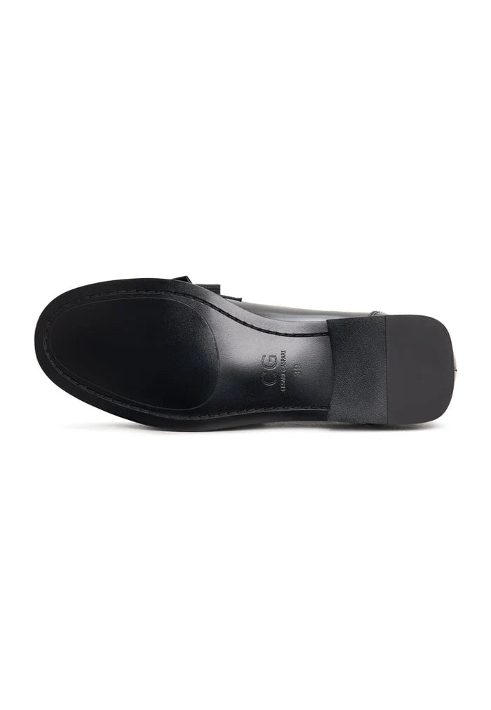 A pair of elegant patent black women's shoes with a gold bow, inspired by Dorothy's style.
