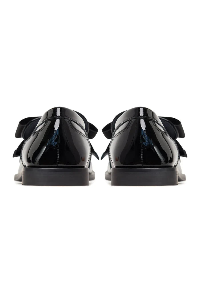 Elegant patent black women's loafers with a sophisticated gold bow detail, inspired by Dorothy's classic style.
