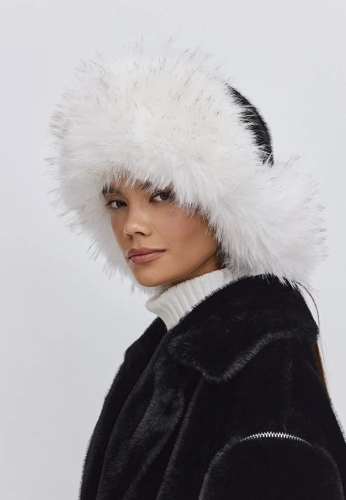 Stylish black and white faux fur hat, perfect for winter fashion, worn by a model in a chic outfit.