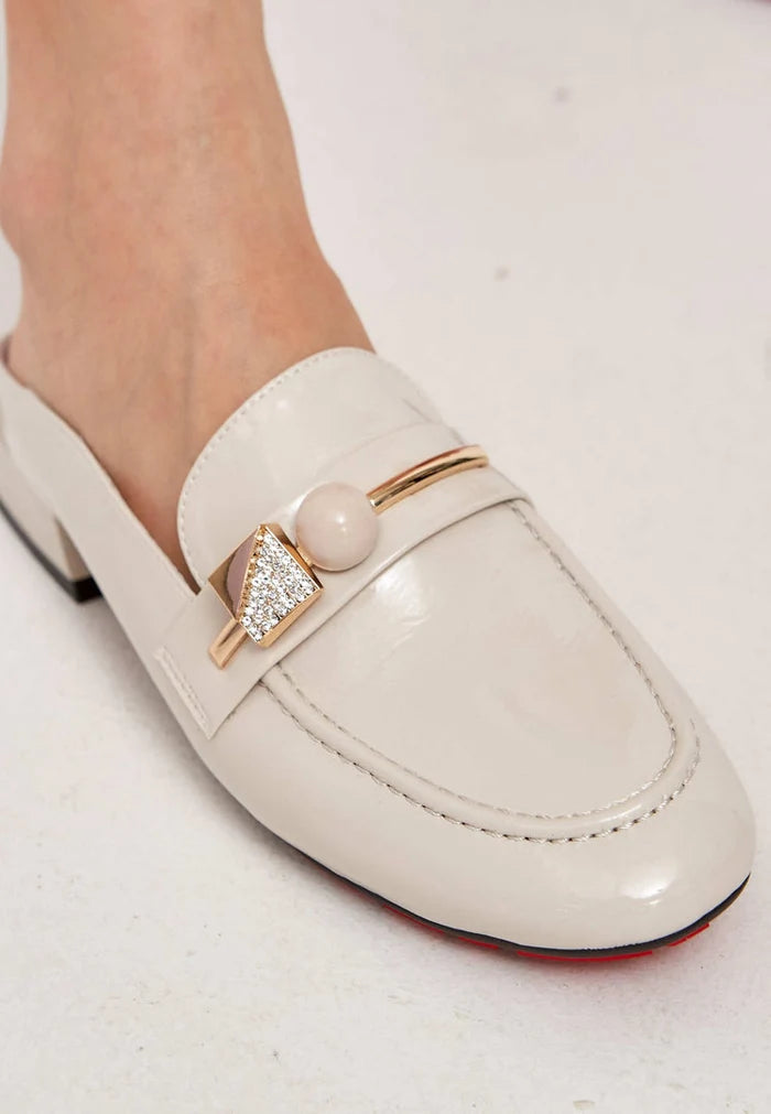 A stylish pair of women's white mule shoes with a glossy charm design, perfect for those seeking elegant and trendy footwear.