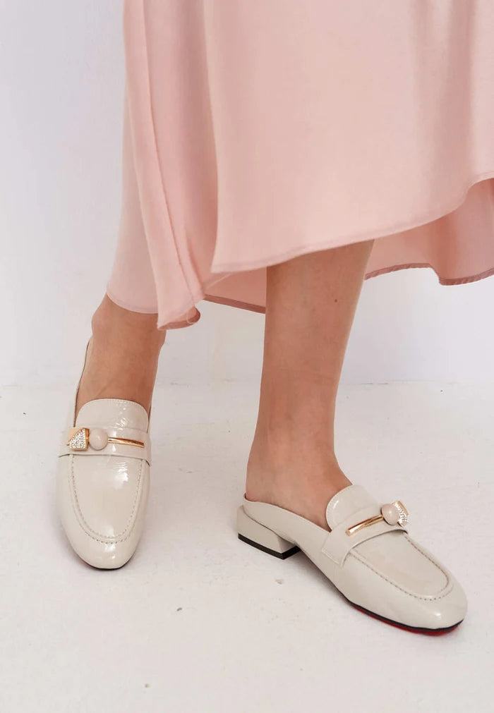 A stylish pair of women's mule shoes featuring glossy charm in elegant white, the perfect trendy footwear choice.