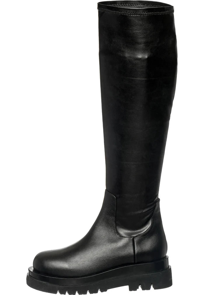 A fashionable woman wearing knee-high leather lug boots, perfect for a stylish and trendy look.