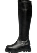 A fashionable woman wearing knee-high leather lug boots, perfect for a stylish and trendy look.