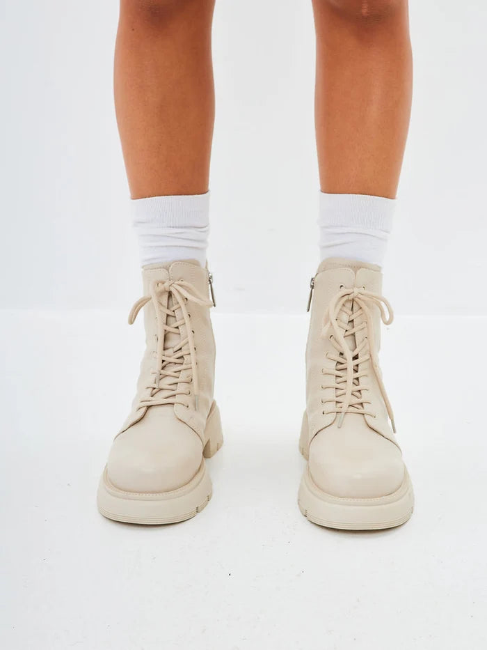 A stylish pair of women's leather platform ankle boots in ivory with high heels.