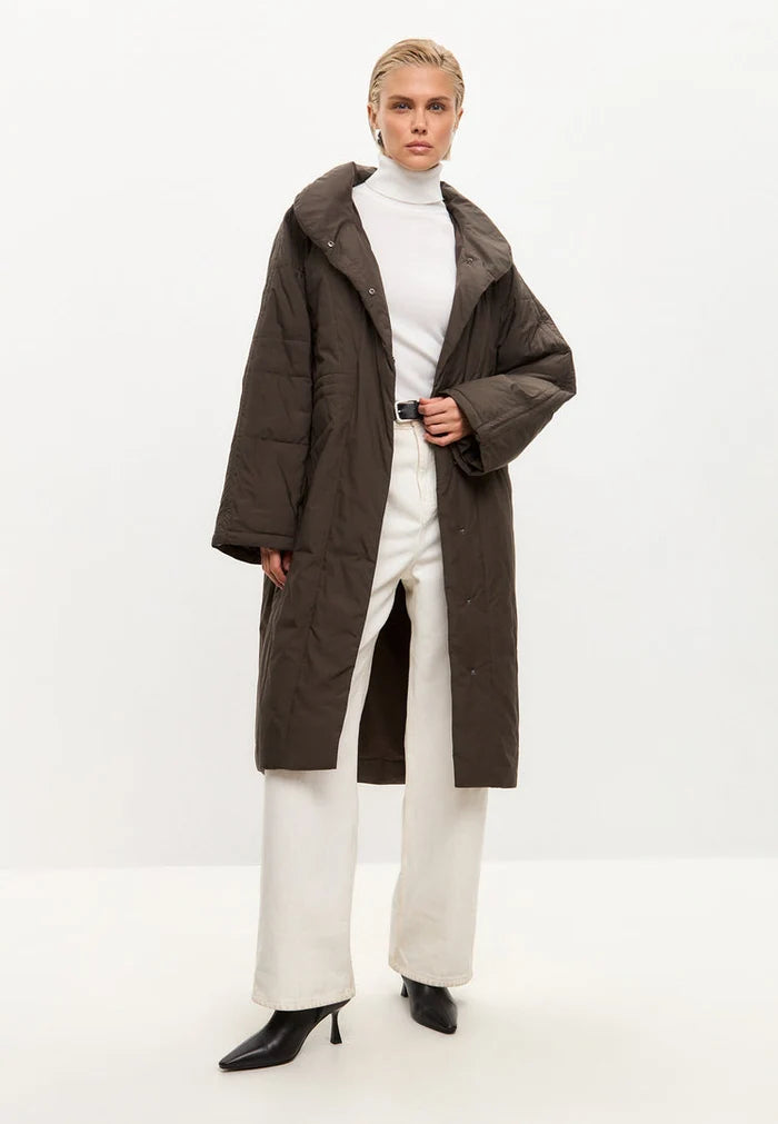 A stylish and fashionable long quilted brown winter jacket for women, perfect for staying warm and chic in the cold weather.