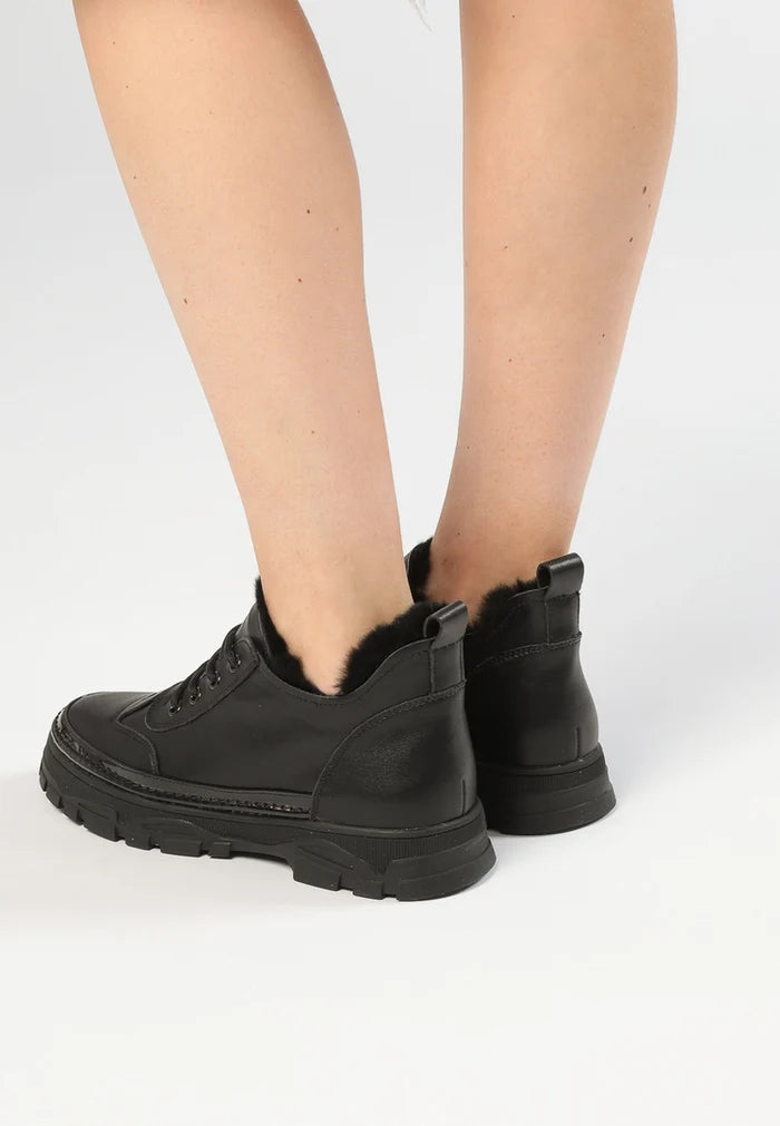 A pair of stylish black chunky sneakers made with Merino wool lining, perfect for chilly weather outings.
