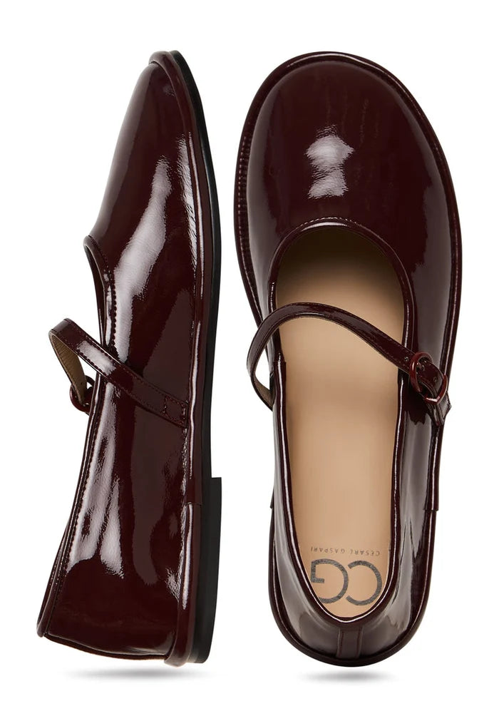 A stylish pair of minimalist flats in Bordeaux color, featuring a charm detail - the perfect minimalist footwear option in Bordeaux.