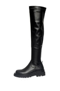 A stylish woman wearing trendy over-the-knee chunky boots, a must-have for this fall/winter season's fashion footwear trends.