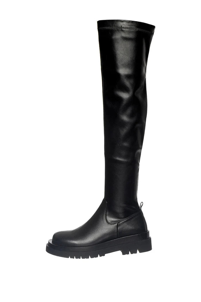 A stylish woman wearing trendy over-the-knee chunky boots, a must-have for this fall/winter season's fashion footwear trends.