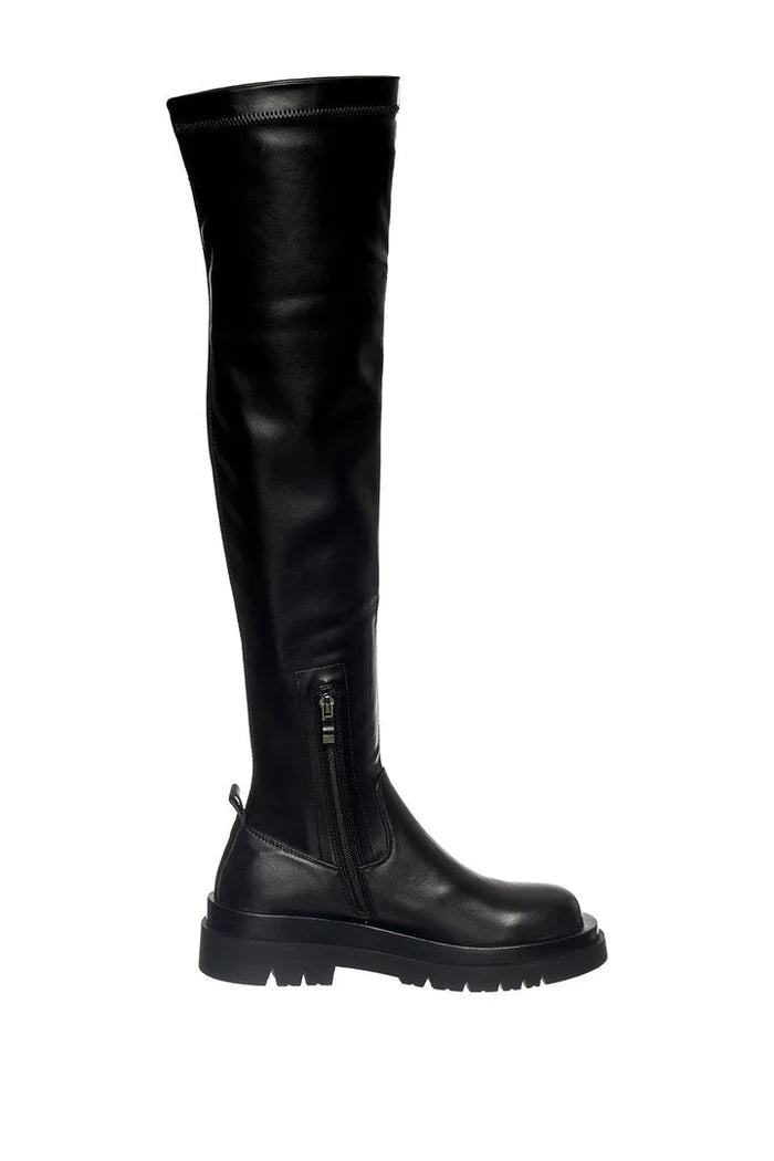 A stylish woman wearing trendy over-the-knee chunky boots, a must-have for fall/winter fashion, showcasing the latest in women's footwear trends.