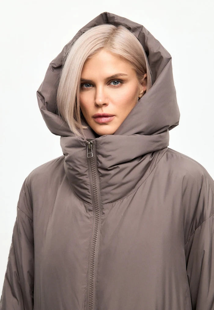 A fashionable women's winter coat in beige featuring an oversized hood, faux fur cuffs, and trendy puffer design.
