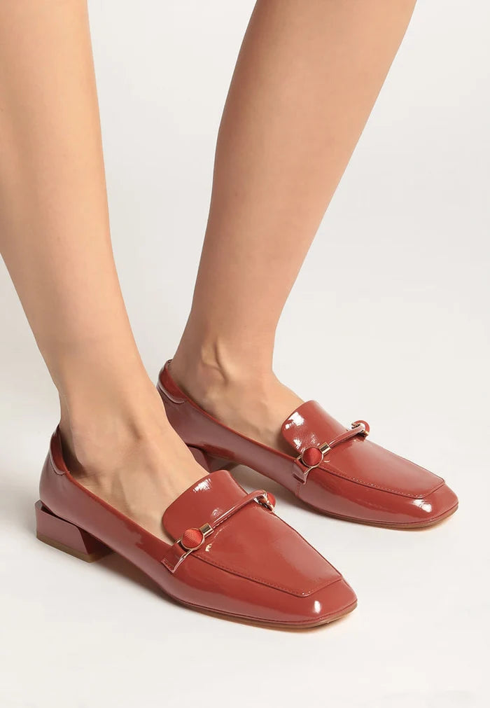 A pair of patent leather loafers with metallic accents in bright orange, trendy and stylish leather slip-on shoes, perfect for fashionable looks.