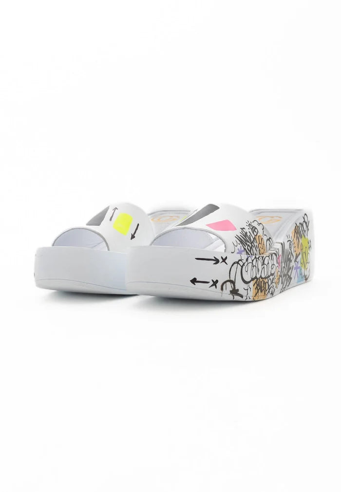 A close-up of stylish white platform mule shoes on a wooden floor, perfect for a chic and trendy look.