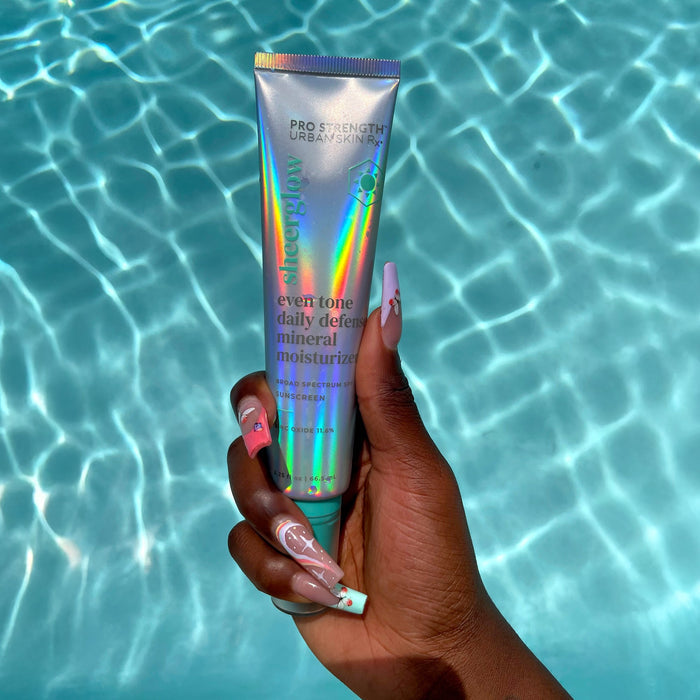 Woman holding a tube of USRx Mineral Moisturizer against a light blue background
