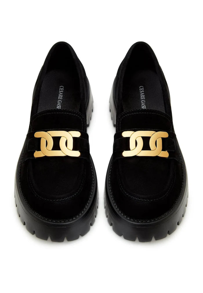 A stylish pair of chunky black loafers with a golden chain accent, crafted from luxurious suede - the perfect choice for fashionable footwear.