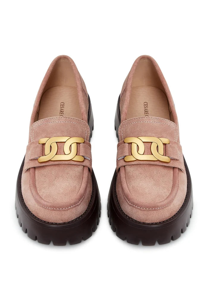 A trendy pair of women's chunky suede loafers in pink with golden chain details.