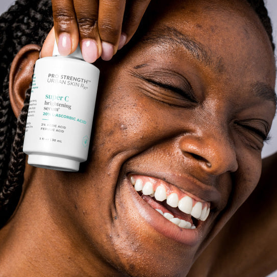 Woman holding a jar of USRx Super C Brightening Serum next to her face