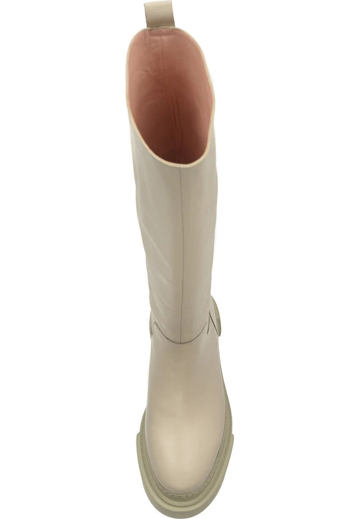 A fashion-forward woman wearing tall leather chunky sole beige boots, a stylish choice in women's fashion footwear.